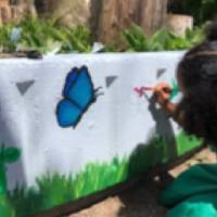 student painting butterfly on the Shawmut Hills sycamore circle mural